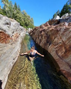 a woman is standing in the water near some rocks