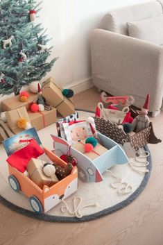 there is a christmas tree in the corner with many boxes and toys on the floor