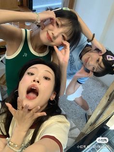 three young women standing in front of a mirror with their hands on their faces and one holding her mouth open