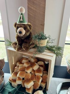 a teddy bear sitting on top of a wooden box filled with marshmallows