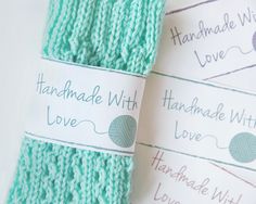 two green knitted items with handmade love labels attached to the yarn on them