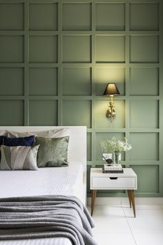 a white bed sitting next to a green wall