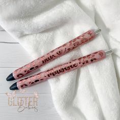 two pink and black pens sitting on top of a white towel next to each other