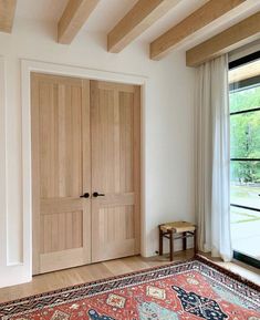 an empty room with two wooden doors and a rug on the floor in front of it