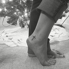 a person with a cross tattoo on their foot next to a christmas tree in black and white