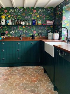 a kitchen with green cabinets and floral wallpaper on the walls is pictured in this image