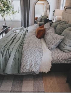 a large bed sitting in a bedroom next to a window with lots of pillows on top of it