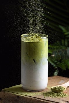 a green and white drink is being sprinkled with powder