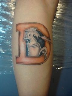 a tattoo on the leg of a person with a horse and letter d