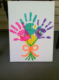 handprints on a white card with orange ribbon and bow in front of it