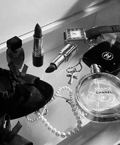 black and white photograph of chanel perfume bottle, necklace, keychain, purse