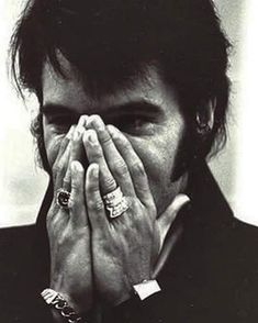 black and white photograph of a man covering his face with both hands while wearing rings