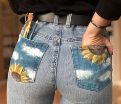 a woman wearing jeans with sunflowers painted on the side and holding a pen in her pocket