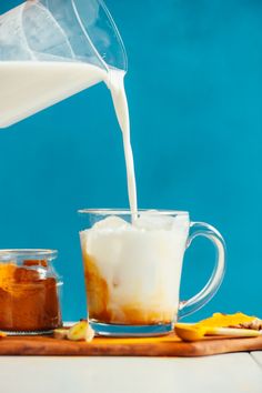 a pitcher pouring milk into a glass mug