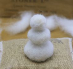 a small white snowman sitting on top of a piece of burlock