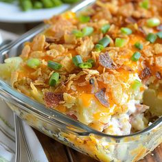 a casserole dish with meat and vegetables in it on a wooden table next to green beans