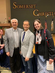 three people standing next to each other in front of a sign that says somerset christian