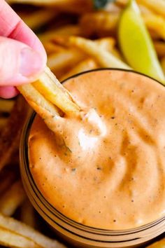 a person dipping some fries into a small bowl