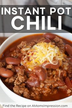 a white bowl filled with chili and cheese on top of a wooden table next to an instant pot