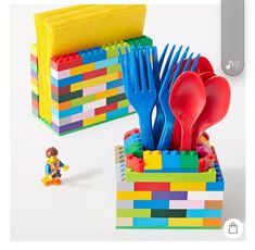 lego blocks and plastic utensils are in a box with a toy figure next to it