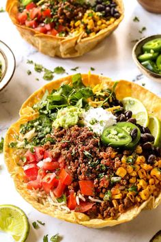 mexican food is served in tortilla bowls with limes and cilantro