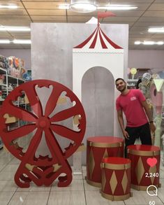 a man is standing next to some red and gold decorations in a store with a ferris wheel