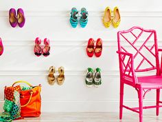 there are many pairs of shoes hanging on the wall next to a chair and purse