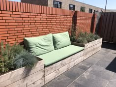 a couch sitting on top of a wooden bench next to a brick wall