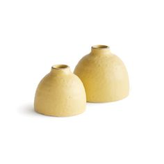 two yellow vases sitting next to each other on a white surface with no one around them