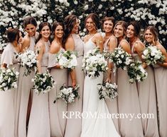 a group of women standing next to each other in front of white flowers and greenery