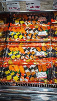 many different types of sushi are displayed in plastic containers on the shelves at a store