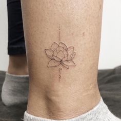 a woman's lower leg with a small flower tattoo on her left side ribcage