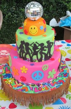 a multi - colored cake with peace signs on it is sitting on a colorful tablecloth