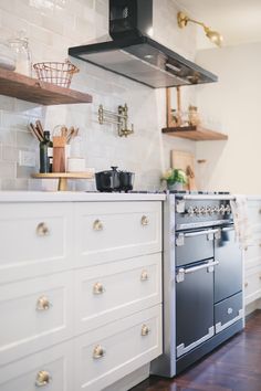 a stove top oven sitting inside of a kitchen next to a wooden floor and white cabinets