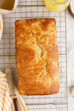 a loaf of bread sitting on top of a cooling rack next to a cup of tea