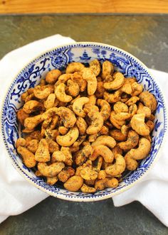 a blue and white bowl filled with cashews on top of a table next to a napkin