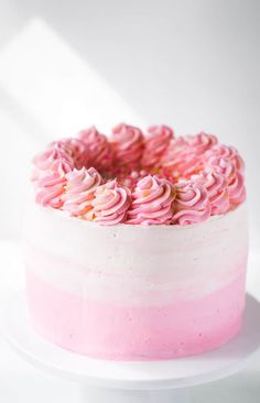 a cake with pink frosting and sprinkles sitting on top of a white plate