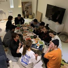 a group of people sitting around a table with food in front of them on the floor