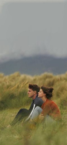 two people are sitting in the grass looking up