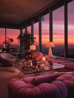 a living room filled with furniture next to tall windows at sunset or sunrise in the city