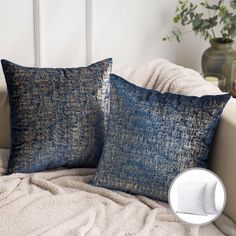 two blue pillows sitting on top of a white couch next to a potted plant