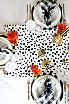 the table is set with black and white plates, silverware, napkins, and flowers