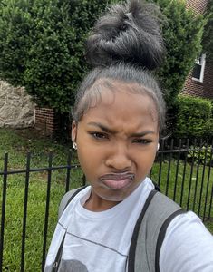 a woman with grey hair wearing a backpack and sticking her tongue out to the side