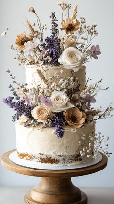 a three tiered cake with white frosting and fresh flowers on the top layer