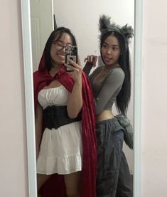 two women are taking a selfie in the mirror while wearing costumes and holding a camera