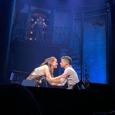 a man and woman on stage in front of a staircase