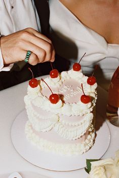 a person cutting into a cake with cherries on it at a wedding reception,