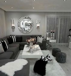 a living room filled with gray couches and white coffee table surrounded by black and silver decor