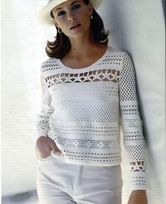 a woman leaning against a wall wearing a white hat and sweater with crochet