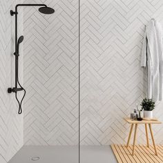 a white tiled bathroom with a shower and standup shower head in the corner, next to a wooden stool